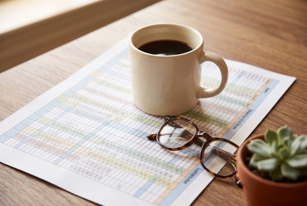 Coffee and reading glasses on a printed spreadsheet